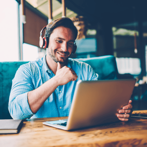 man at laptop with headphones on in remote work meeting